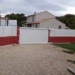 Portail aluminium de couleur blanche. sur muret rouge