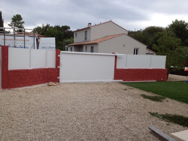 Portail aluminium de couleur blanche. sur muret rouge