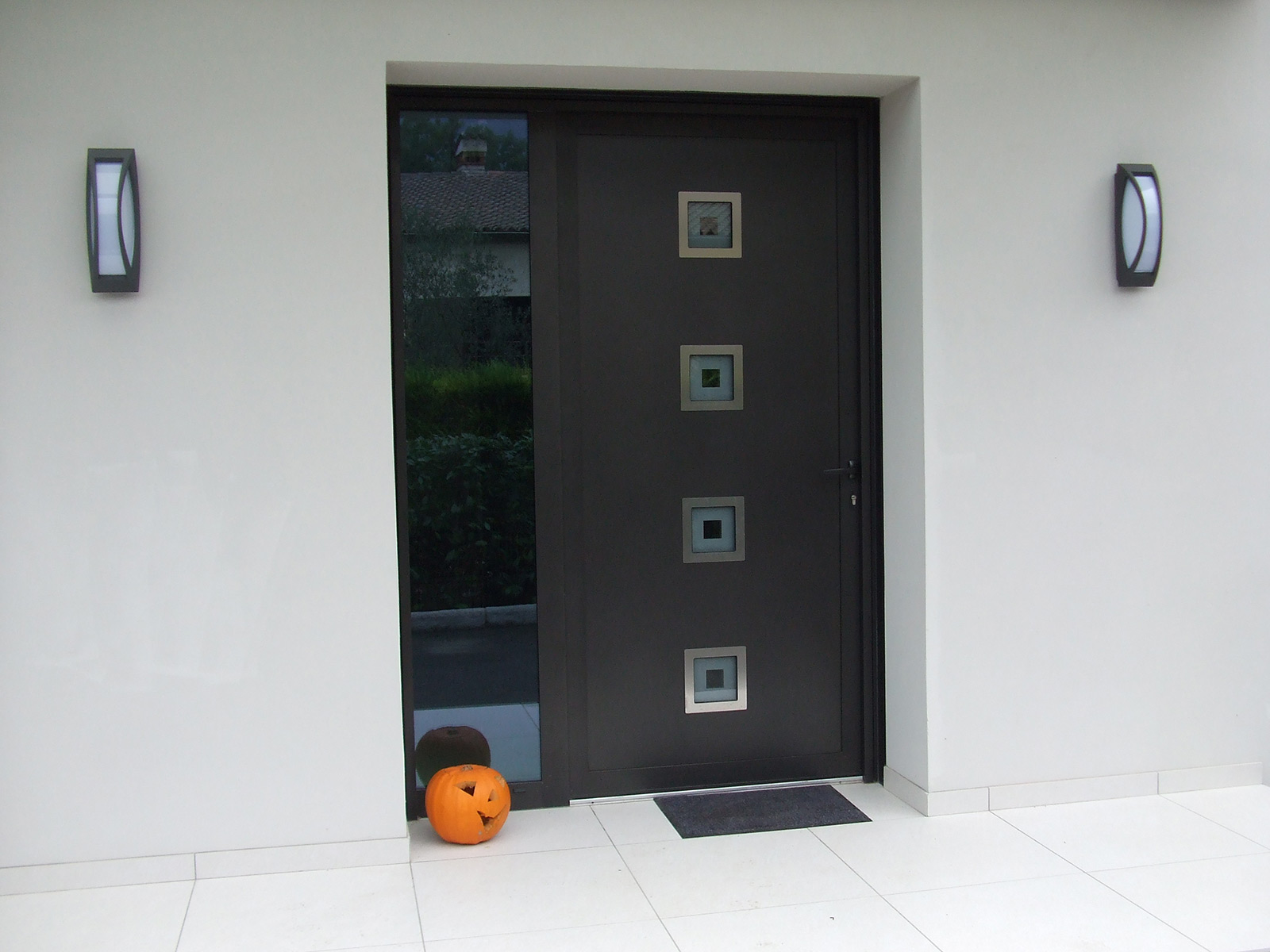 Photo d"une réalisation d'une porte d'entrée moderne avec fixe latéral et insert inox