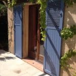 volets battants bleus sur pergola en bois avec vigne