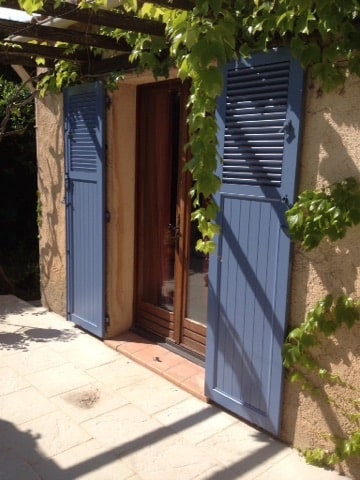volets battants bleus sur pergola en bois avec vigne